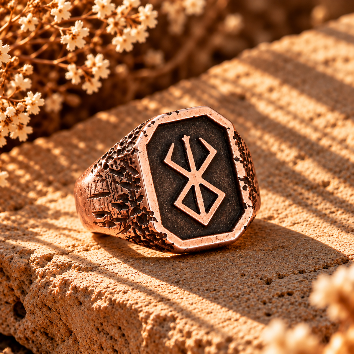 Rose gold rune signet ring with dark inlay and raised runic symbol.