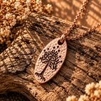 Silver-tone oval White Tree of Gondor-inspired pendant with a hammered-style texture on rustic wood.