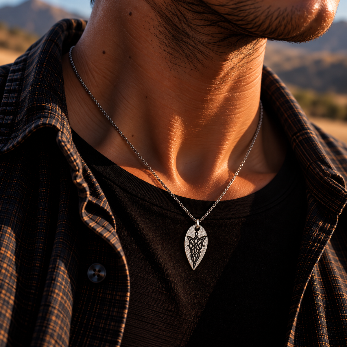 Silver-tone leaf-shaped Evenstar-inspired necklace worn over a black shirt at sunset.