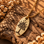 Gold-tone hammered-style White Tree of Gondor-inspired pendant with a branching tree motif on sunlit wood.